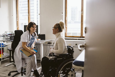 Smiling female medical expert looking at disabled woman talking in medical clinic