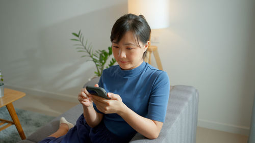 Young woman using mobile phone at home