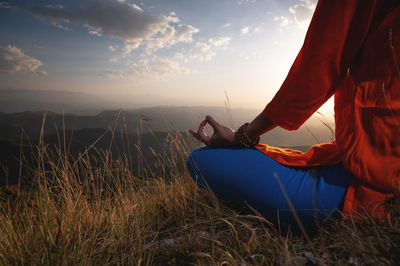 Close-up of a woman and female hands sitting in a lotus position, yoga outdoors in the grass at