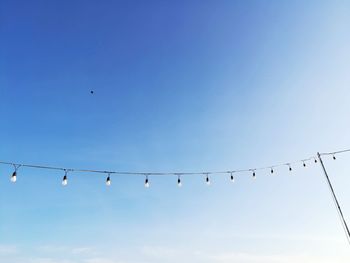 Low angle view of birds flying against clear blue sky