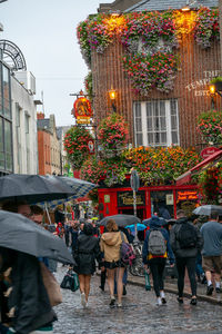 Rear view of people walking on street against buildings in city