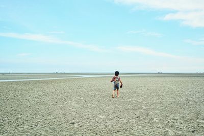 Rear view of boy walking at beach