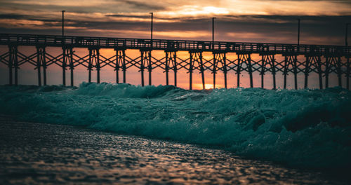 Pier over sea against sky during sunset