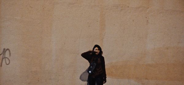 Portrait of a young woman standing against wall