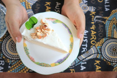 Slice of delicious coconut layer cake with a woman's hand.topview.