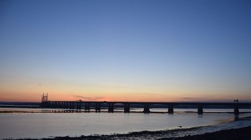 Bridge over sea against sky during sunset