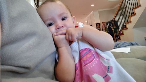 Portrait of cute baby girl sitting on bed at home