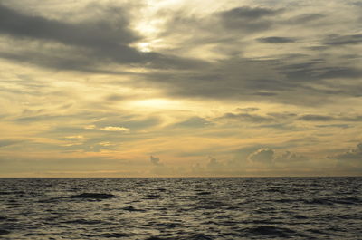 Scenic view of sea against cloudy sky at sunset