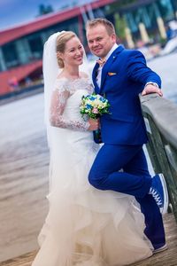 Happy wedding couple standing on footbridge at harbor