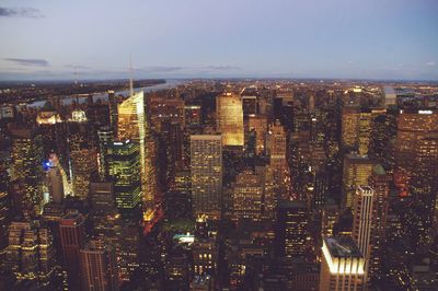 Aerial view of city lit up against sky