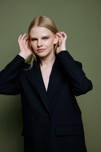 Portrait of young businesswoman standing against gray background