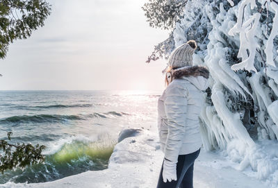 Woman standing by sea against sky during winter