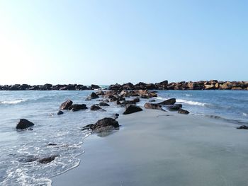 Rocks on beach against clear sky