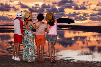 Full length of women standing on shore against sky during sunset