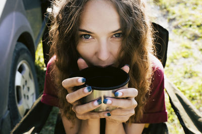 Close-up portrait of woman having drink at campsite
