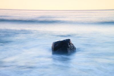 Romantic peaceful morning at sea. boulders sticking out from smooth wavy sea. first hot sun rays.