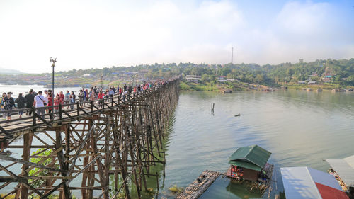 People on bridge over river against sky