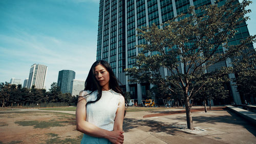 Young woman standing against modern building in city