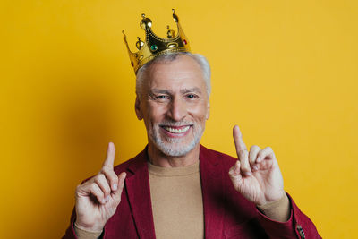 Portrait of smiling man gesturing against yellow background