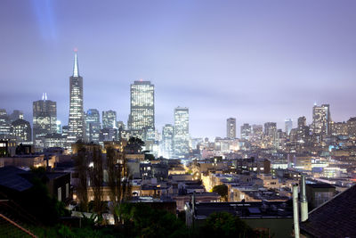 Illuminated buildings in city against sky