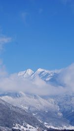 Low angle view of snowcapped mountains against blue sky