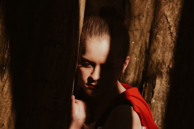 Close-up portrait of young woman against tree trunk