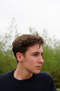 Young man looking away against plants