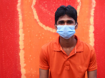 Portrait of man standing against red wall