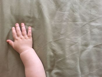 Cropped hand of baby on bed