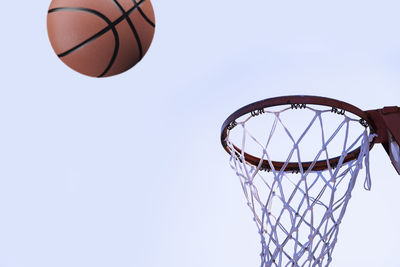 Low angle view of basketball by hoop against clear sky