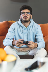 Concentrated young man playing video game in living room