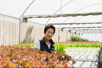 Portrait of young woman standing against plants