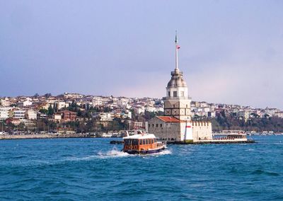 Boat in bosphorus strait by maiden tower against sky