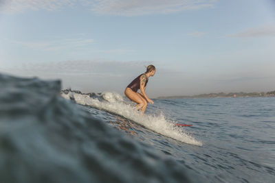 Young woman surfing at sunrise