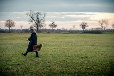 Side view of woman walking on grassy landscape