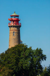 Low angle view of lighthouse by building against clear blue sky