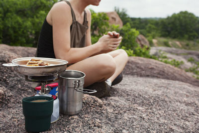 Low section of woman sitting by stove on rock