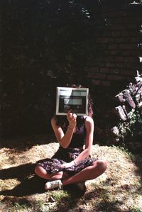 Midsection of man photographing camera while sitting on land