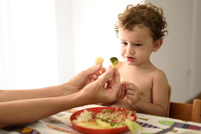 Boy eating food on table at home