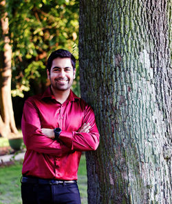 Portrait of young man standing on tree trunk