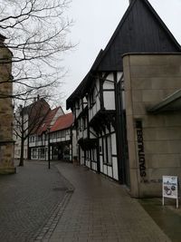 Empty street amidst buildings in city against sky