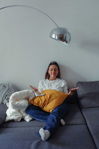 Young woman looking down while sitting on bed at home