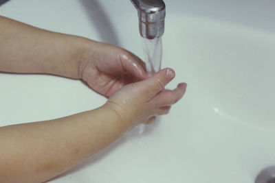 Close-up of hand touching water in bathroom
