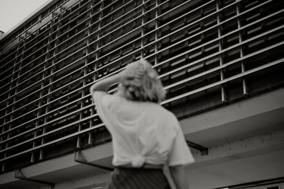 Rear view of woman standing by window