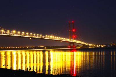 Illuminated bridge over river at night