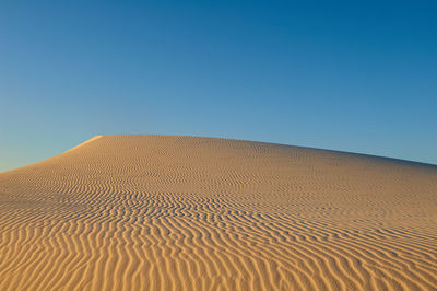 Sand dunes against clear blue sky