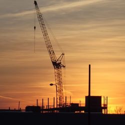 Low angle view of crane against sky during sunset