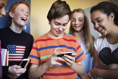 Happy students using cell phones in high school