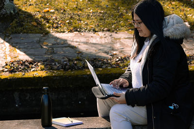 Woman using mobile phone while sitting on camera