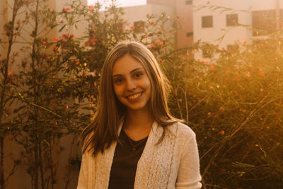 Portrait of smiling young woman standing against plants